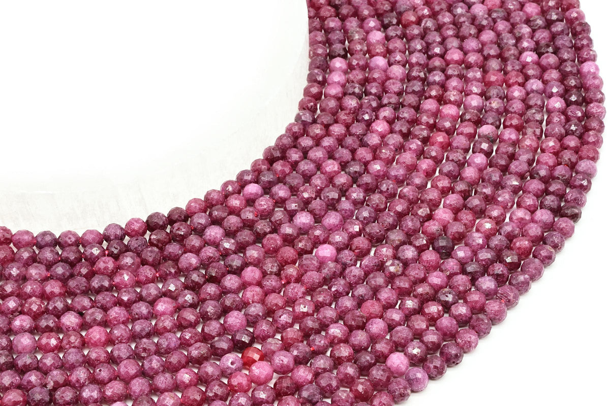 Fils de perles rondes facettées de rubis rose et rouge posés côte à côte
