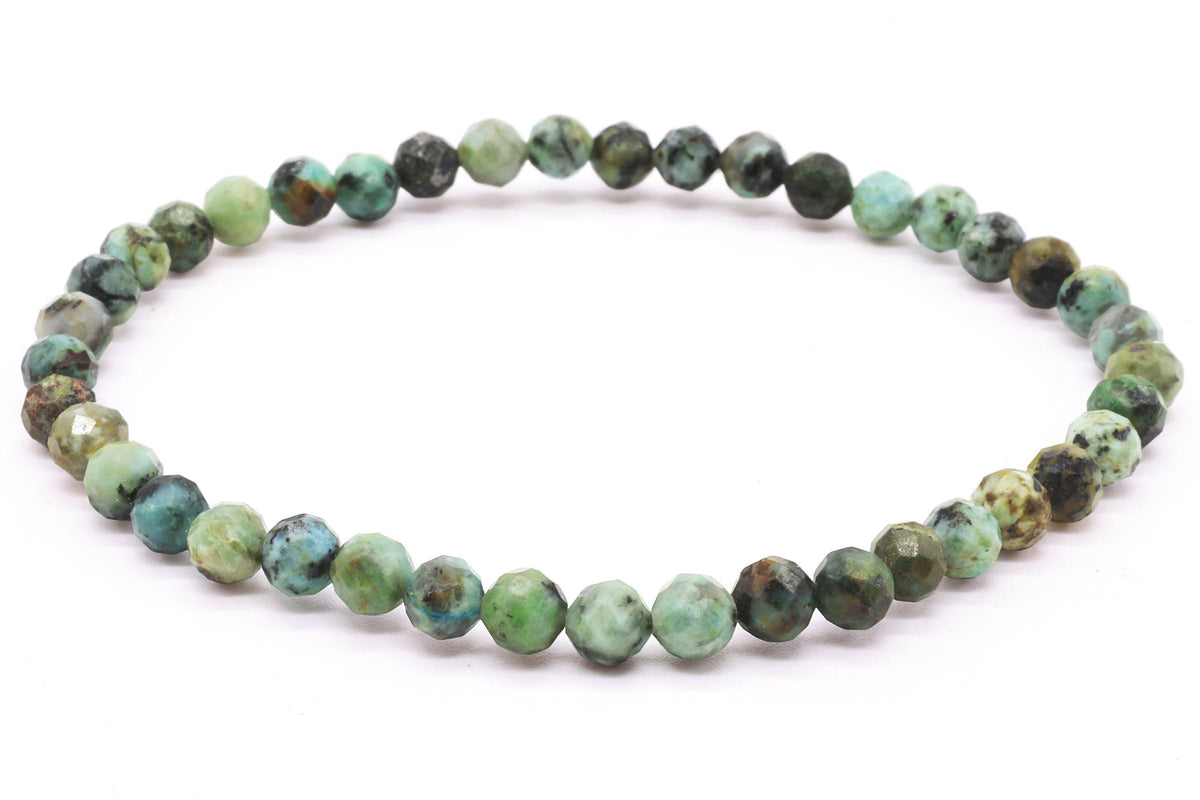 Bracelet élastique de perles facettées de Turquoise Africaine aux nuances vertes et bleutées sur fond blanc