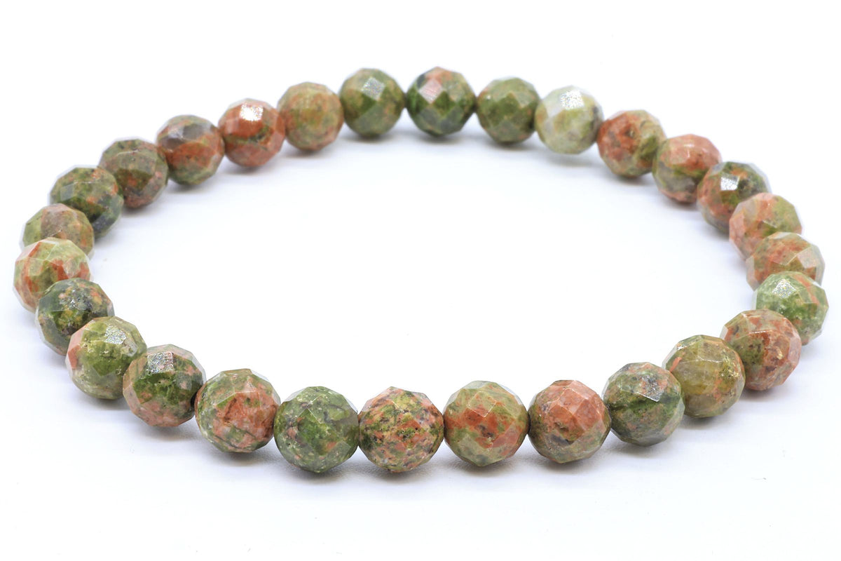 Bracelet de perles facettées en Unakite vert et rose saumon posé sur fond blanc