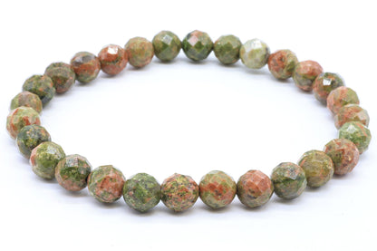 Bracelet de perles facettées en Unakite vert et rose saumon posé sur fond blanc