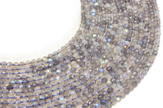 Fils de perles facettées de Labradorite grise aux reflets bleutés sur fond blanc