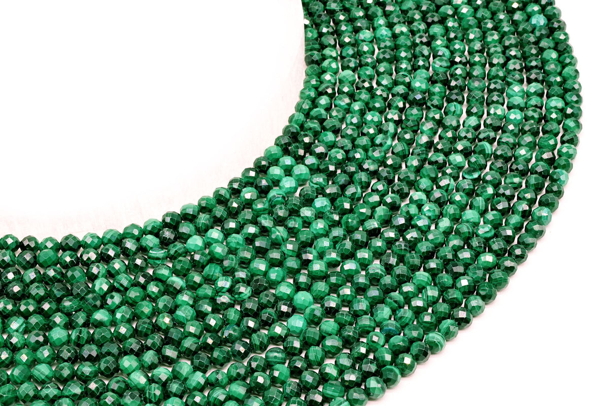 Fils de perles facettées en Malachite vert profond disposés en arc sur fond blanc