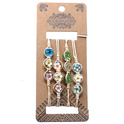 Quatre bracelets sur cordon avec perles de verre contenant des fleurs séchées colorées