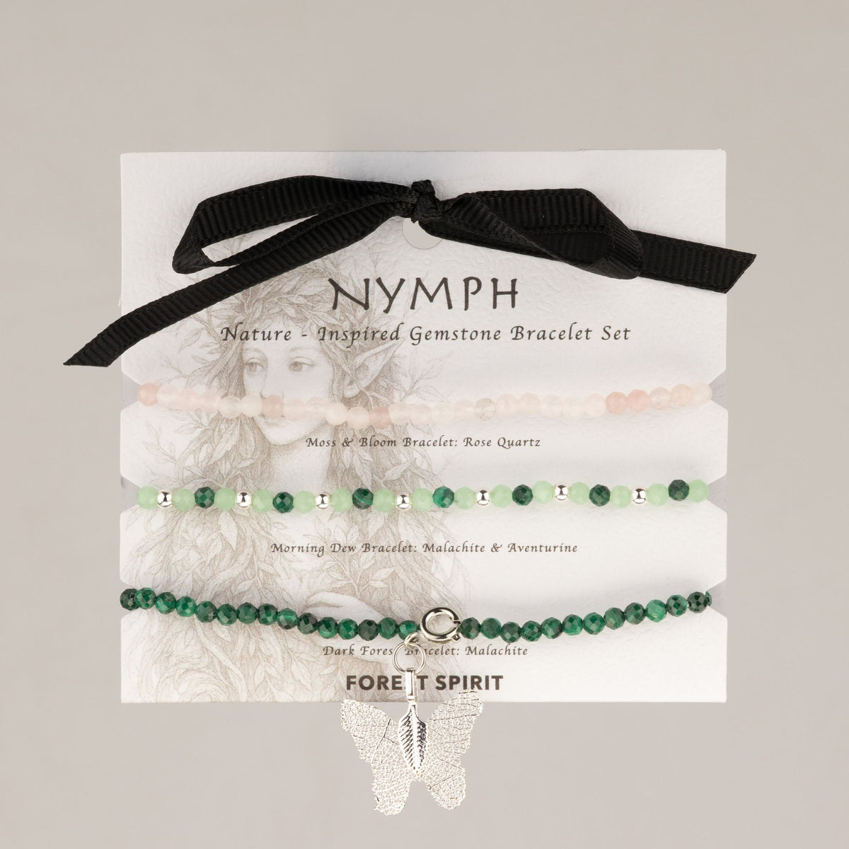 Trois bracelets en quartz rose, malachite et aventurine sur carte illustrée avec ruban noir