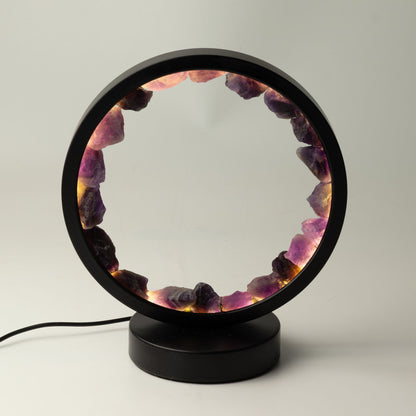 Lampe halo circulaire noire ornée d'un anneau d'améthystes brutes illuminées sur socle