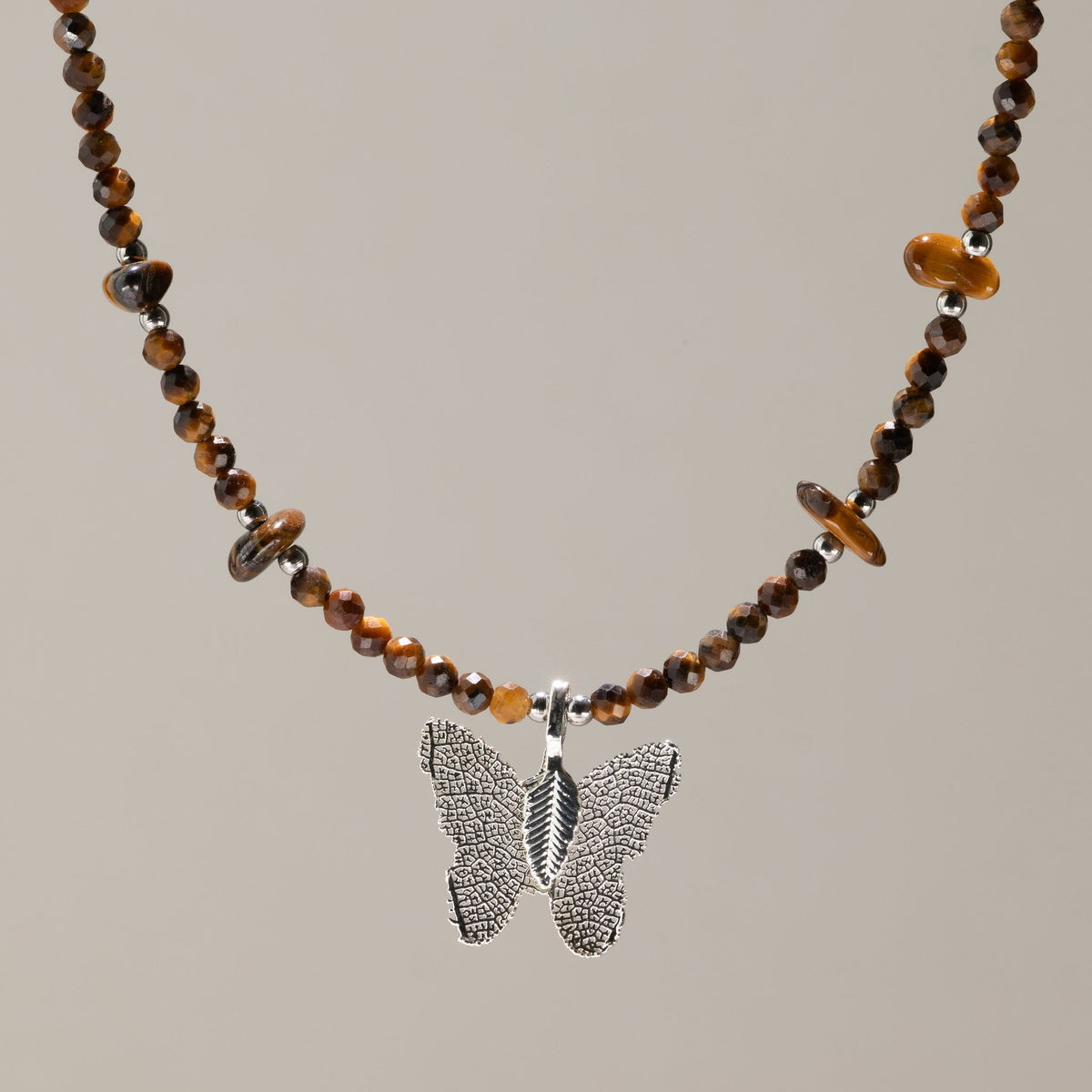 Collier de perles facettées d'Œil de Tigre avec pendentif papillon argenté en feuille