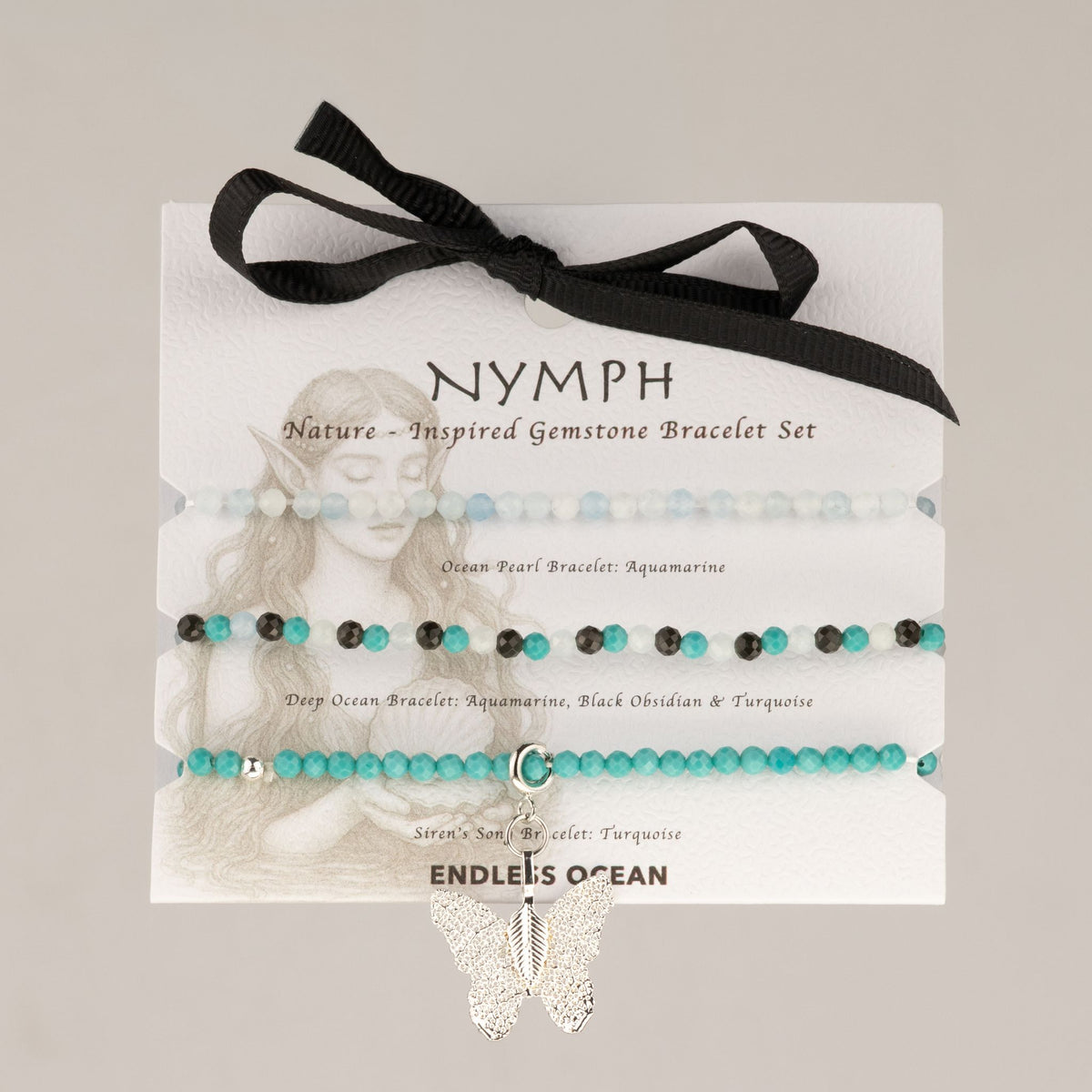 Trois bracelets en aigue-marine, turquoise et obsidienne sur carte illustrée avec ruban noir