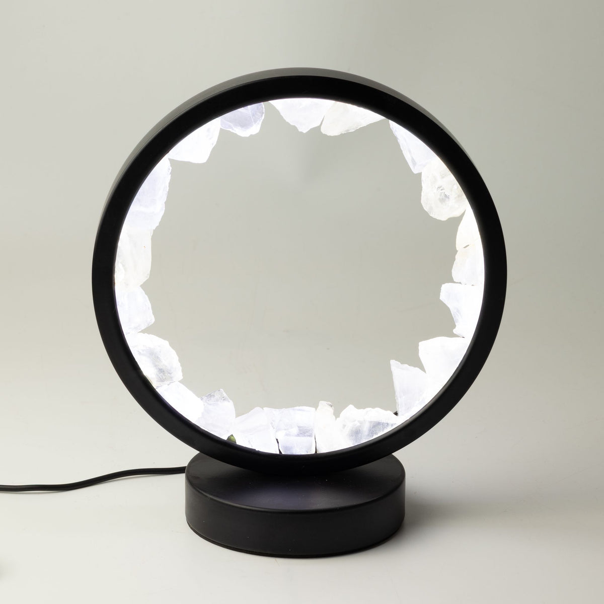 Lampe circulaire noire allumée, bordée de morceaux bruts de cristal de roche
