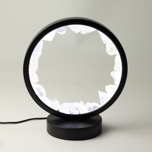 Lampe circulaire noire allumée, bordée de morceaux bruts de cristal de roche