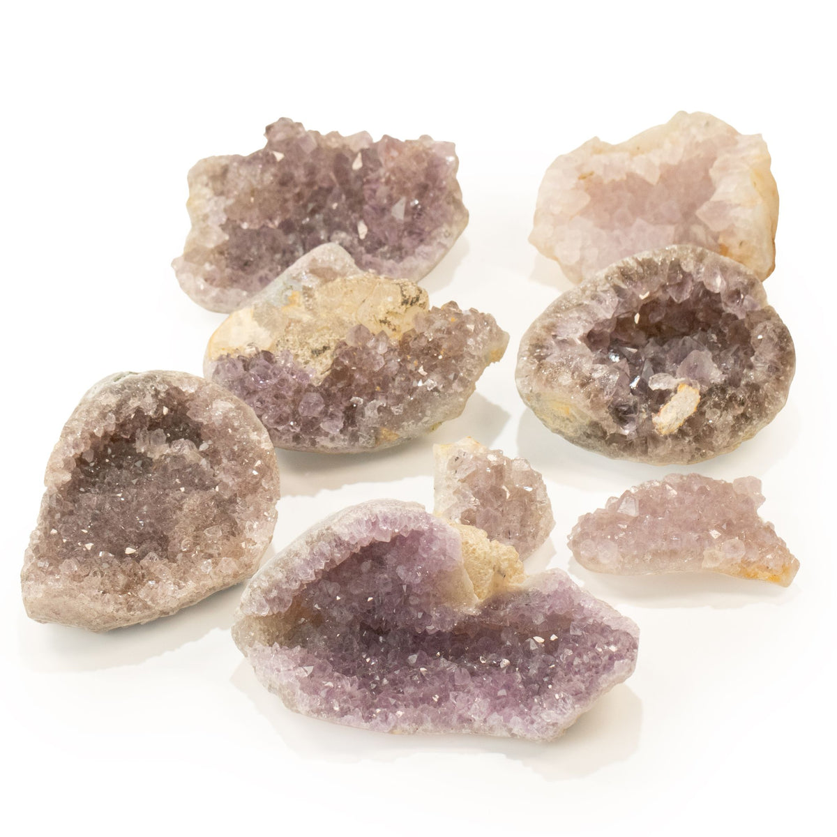 Plusieurs petites géodes d'améthyste ouvertes aux cristaux violets et lilas sur fond blanc