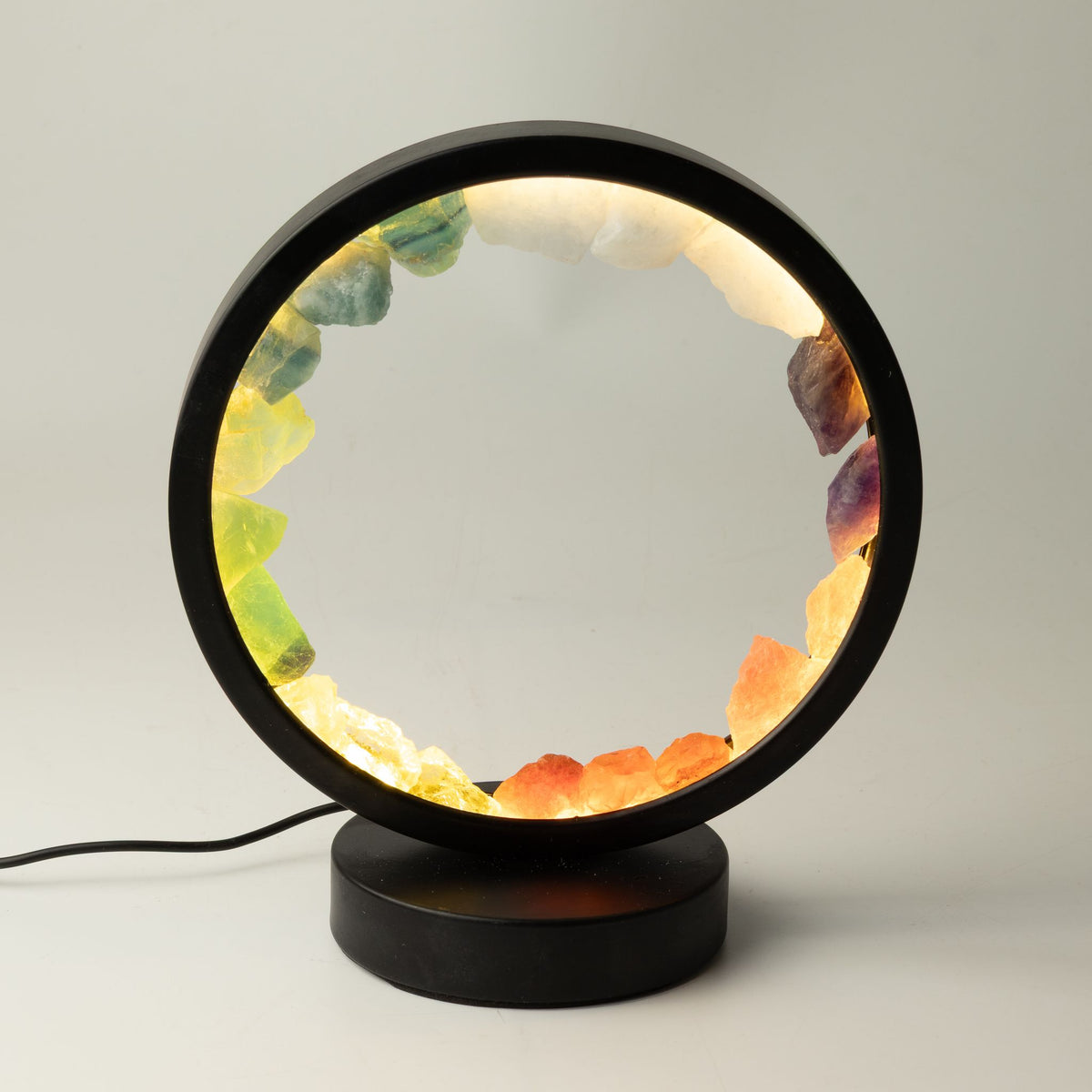 Lampe halo ronde noire allumée ornée de sept pierres brutes colorées en couronne